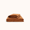 A folded terracotta organic matte sateen sheet set on a white background