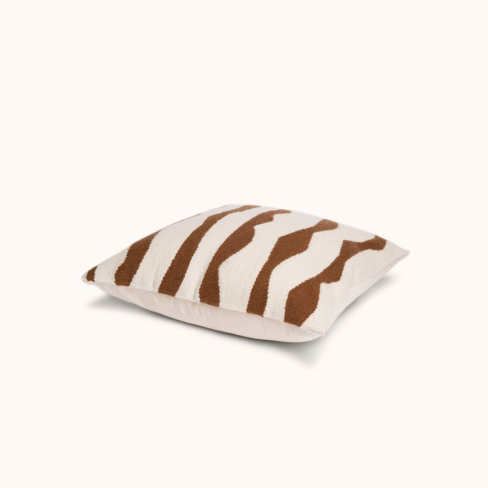 Product shot of the Paso throw pillow, a wool pillow with wavy brown thick stripes against a cream background